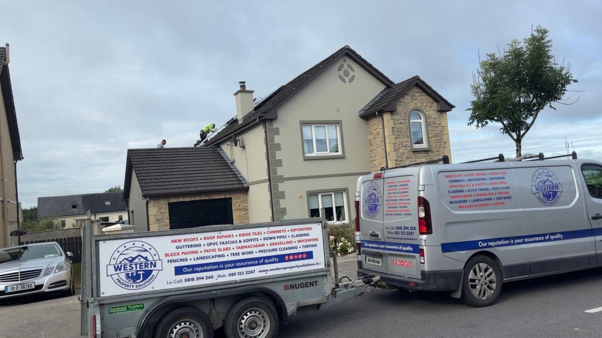 Western Property Solutions crew working on a house roof with the company van and trailer out front