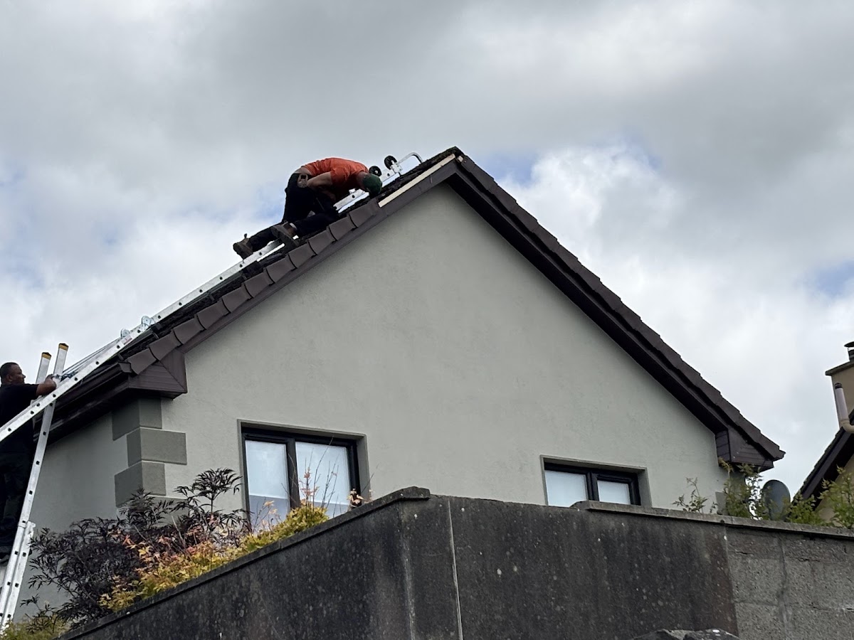 Roofer working at the ridge of a rendered gable
